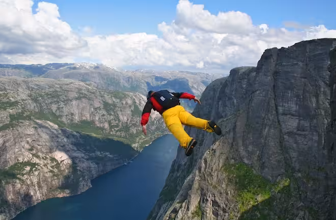 base-jumper falling from cliff down to the fjord