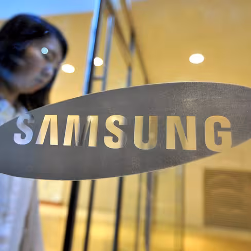 A woman walks past a logo of Samsung Ele