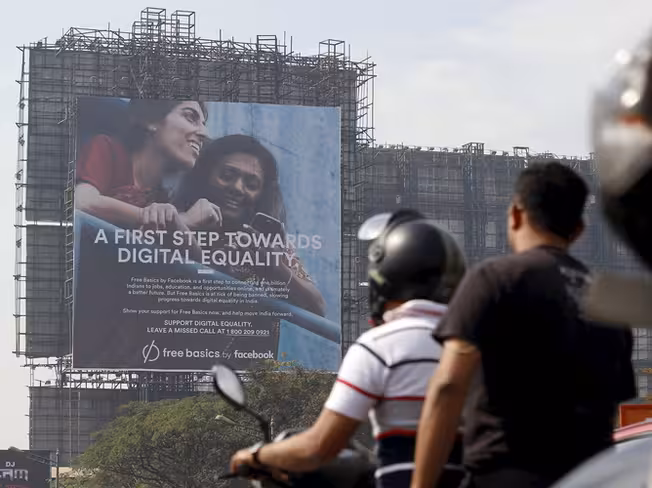 Motorists ride past a billboard displaying Facebook's Free Basics initiative in Mumbai, India