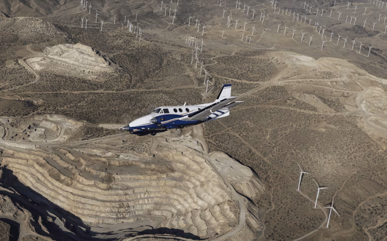 A King Air aircraft banks over the Mojave desert.