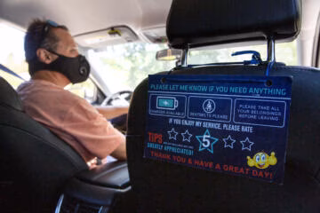 A guest rating and assistance sign hangs from the back of the passenger seat of Hector Castellanos' car, a Lyft and Uber driver of five years, as he drives in Walnut Creek, Calif. on Thursday, May 27, 2021.