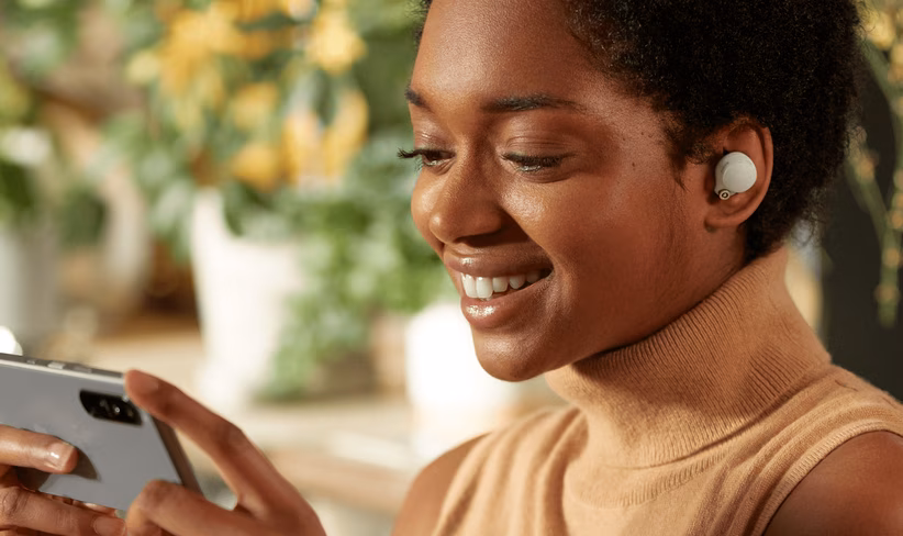 Woman listens to Sony WF-1000XM4 true wireless earbuds while watching something on her phone