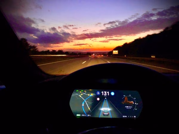 The dashboard seen from inside an electric car at sunset.
