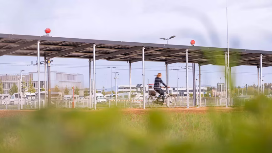 Woman riding bicycle under solar powered roof