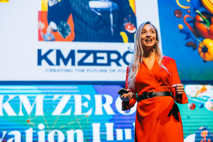 Beatriz Lozano in front of presentation screen on stage