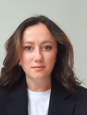 A portrait photo of Dr. Zeliha Guler in a black jacket and white t-shirt
