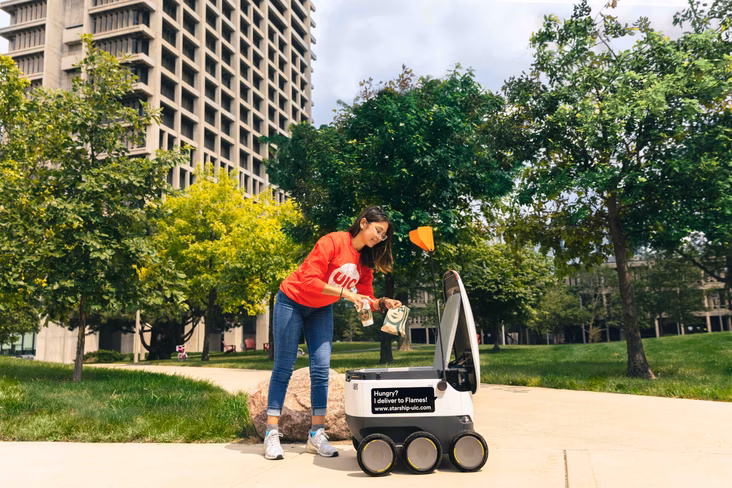 Girl picking up delivery from Starship technologies robot 