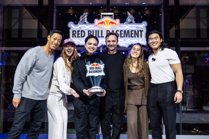 The winner of Red Bull Basement surrounded by the panel of judges and holding his trophy
