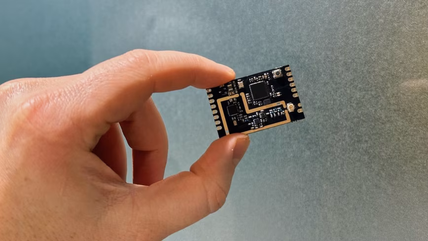 A hand holding the sine.link module for drones