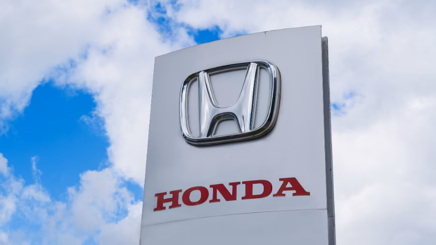 Honda motor company logo and name outside of a car dealership showroom
