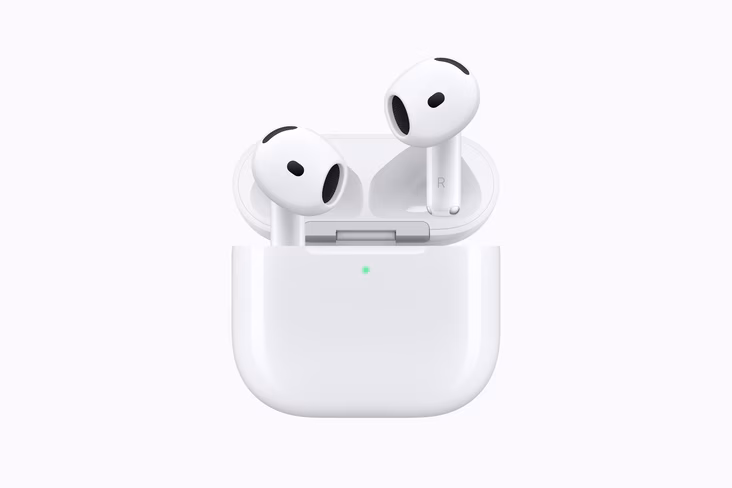 A pair of AirPods 5 standing in an open white charging case with a green status light