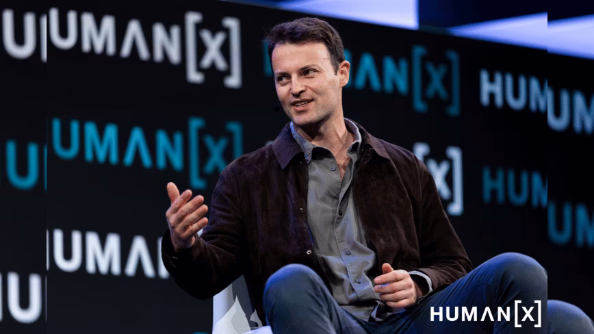 Alex Kendall, co-founder and CEO of Wayve, gesturing as he speaks on stage in front of a HumanX backdrop