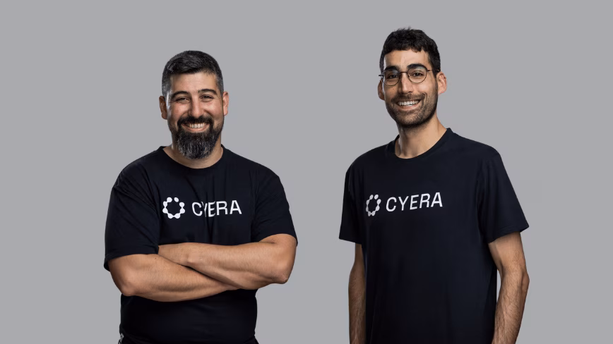 Cyera cofounders Yotam Segev and Tamar Bar-Ilan in black Cyera T-shirts standing side by side against a plain grey background.