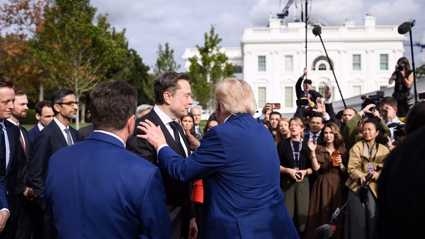 President Donald Trump, seen from behind, greeting tech executives outside the West Wing as photographers and reporters look on.