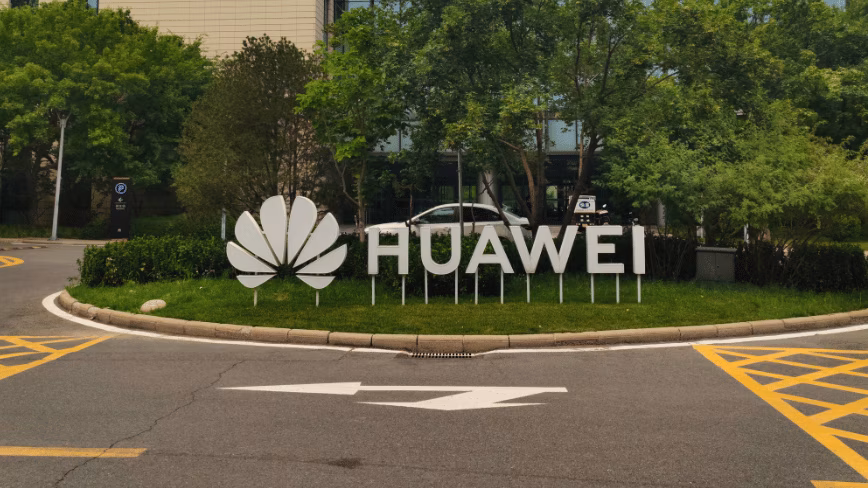 Huawei logo and lettering on a landscaped traffic island outside the glass-fronted Q10 building at the company's Beijing research campus.