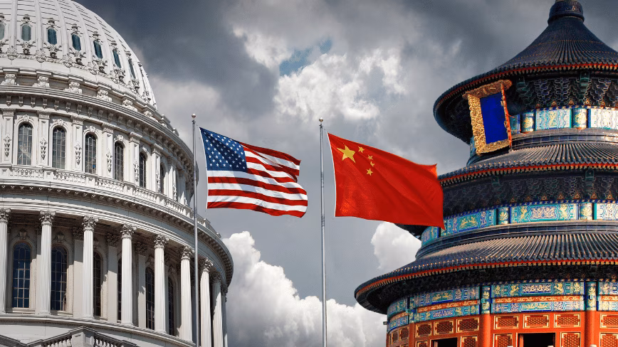 The American flag flying over the US Capitol dome beside the Chinese flag at the Temple of Heaven in Beijing, under a grey sky.