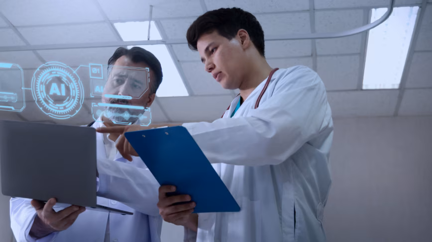 Two people in white coats looking at a laptop, with a glowing blue AI graphic overlaid on the scene.