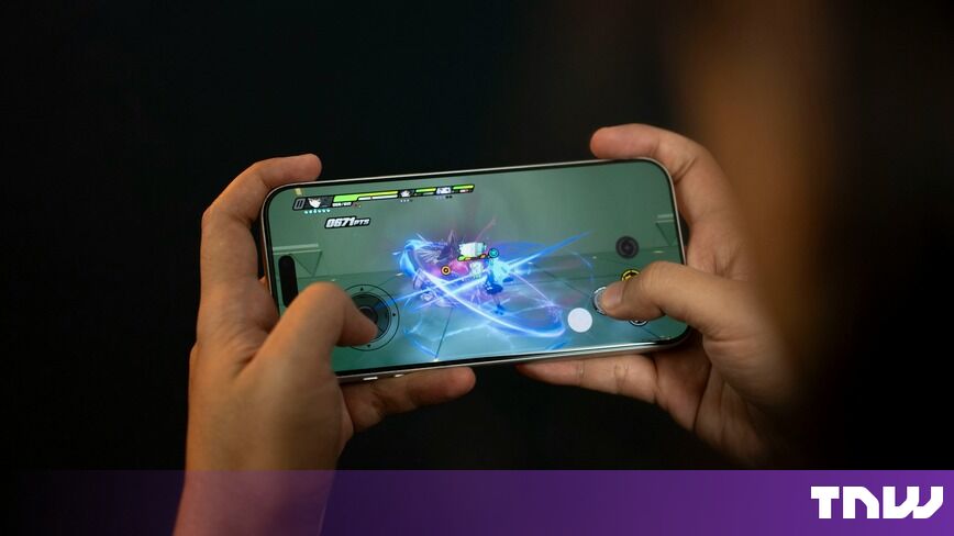 https://media.thenextweb.com/2026/10/hands-holding-smartphone-playing-mobile-game-dark-background.jpg