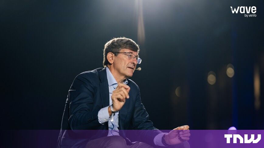 https://media.thenextweb.com/2026/10/vittorio-colao-wave-by-vento-turin-on-stage-gesturing.jpg